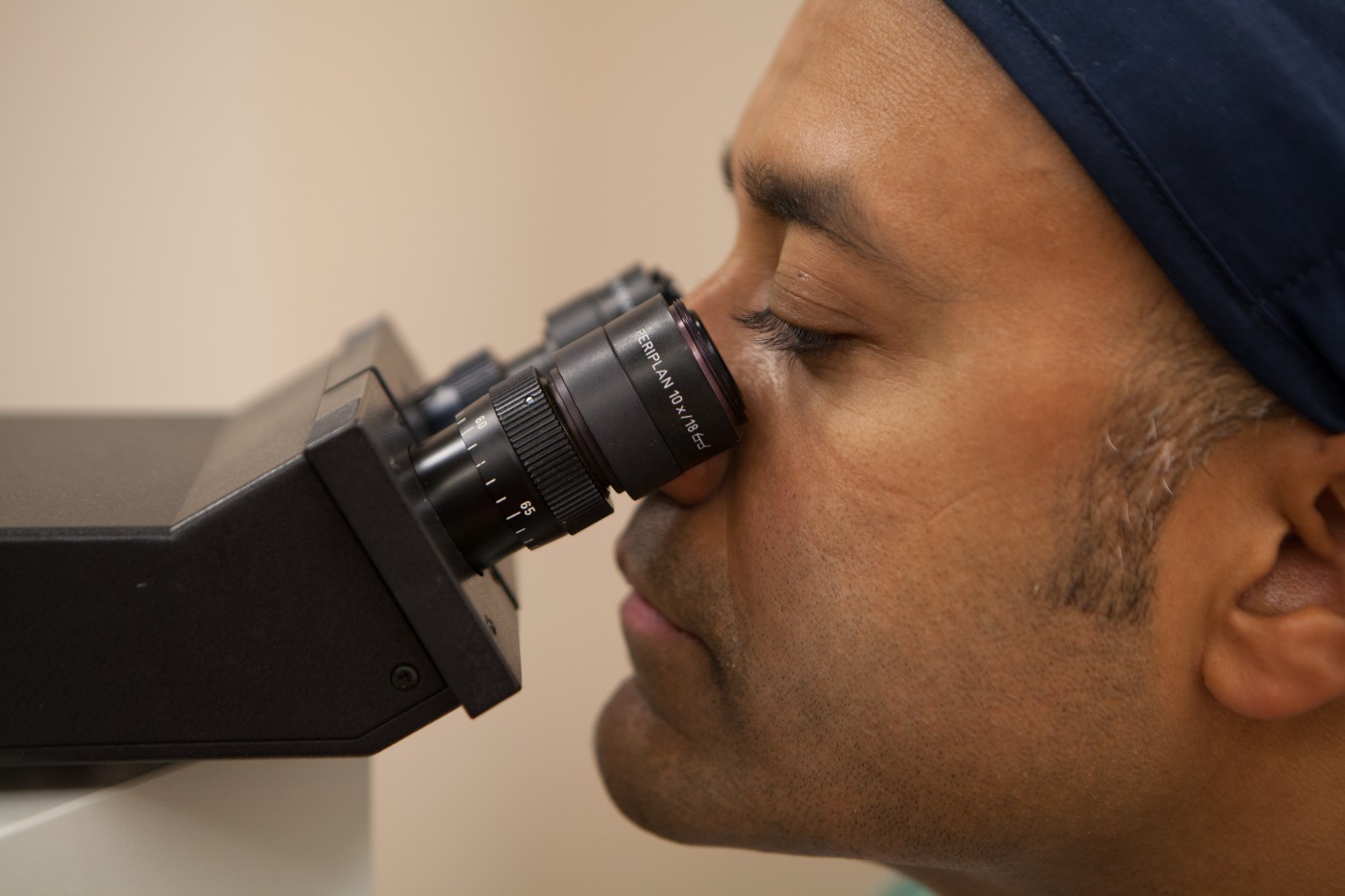 Researcher looking through a microscope in the Pathology lab